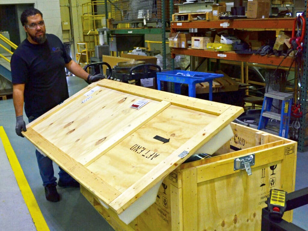 Operator in Factory Opening Crate with Customer Part