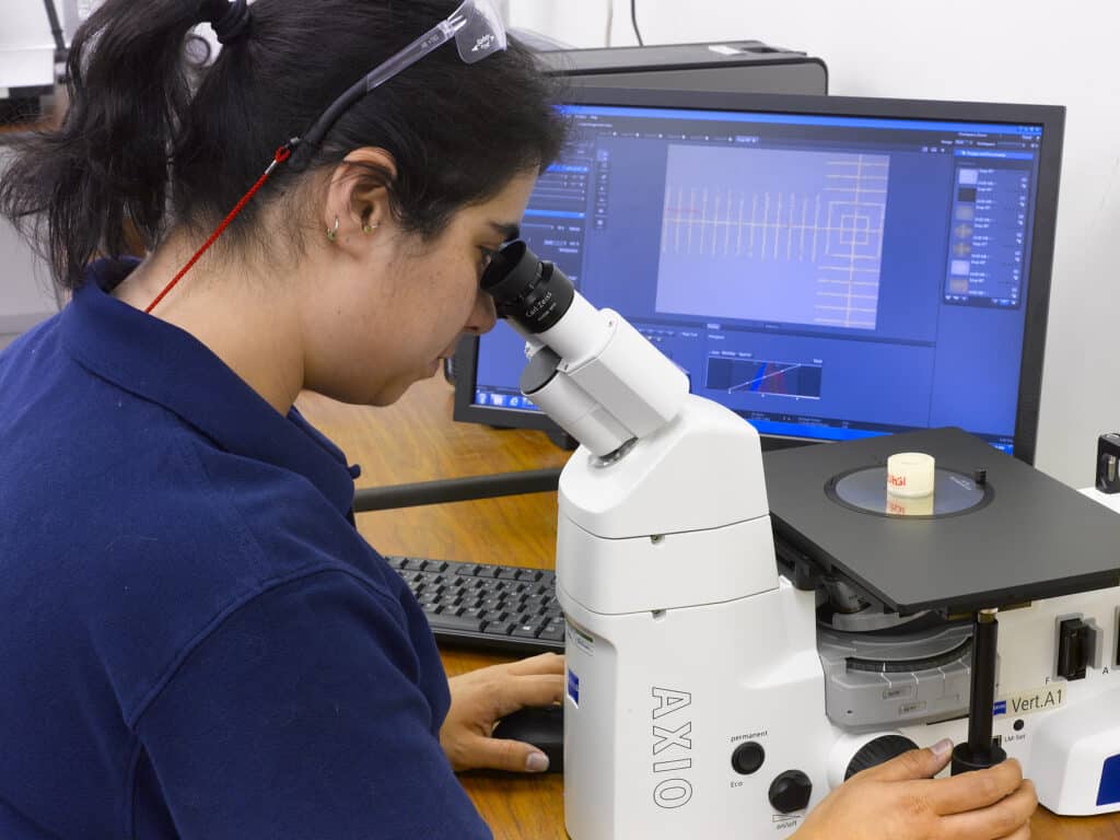 Woman through microscope at PTR's Metallurgical Lab